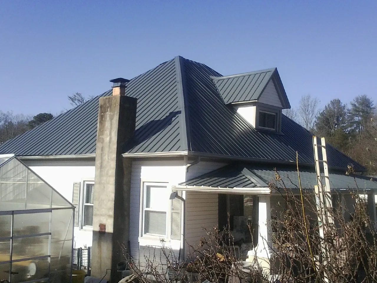 Dark blue standing seam metal roof on a white farmhouse with dormer — Slate & Tile Roof Repair by Roofing Brothers in Paskenta