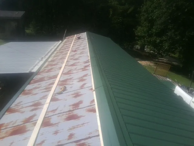 Old rusted panels beside newly installed green metal roofing — Wind Damage Roof Repair by Roofing Brothers in Paskenta