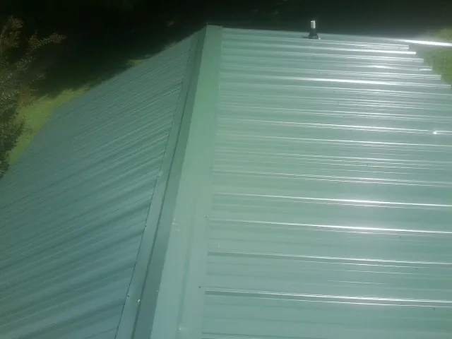 New green metal panels meeting at the ridge of a roof — Flat Roof Repair work by our crew in Paskenta
