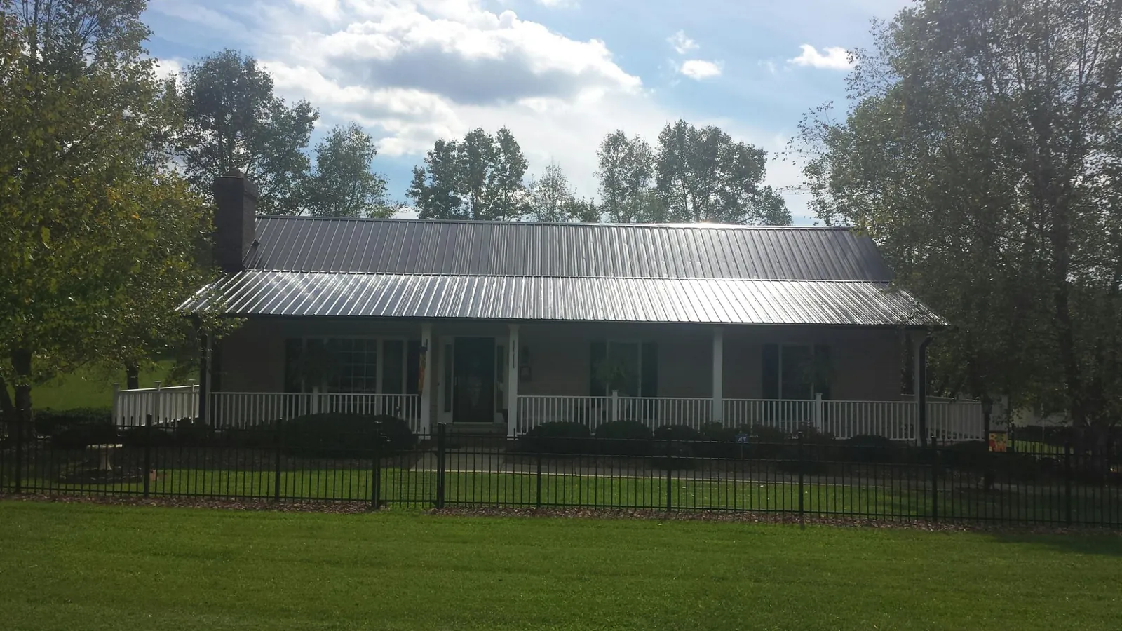 Gray metal roof on a brick ranch with a full width front porch — Gutter Guard Installation work by our crew in Paskenta